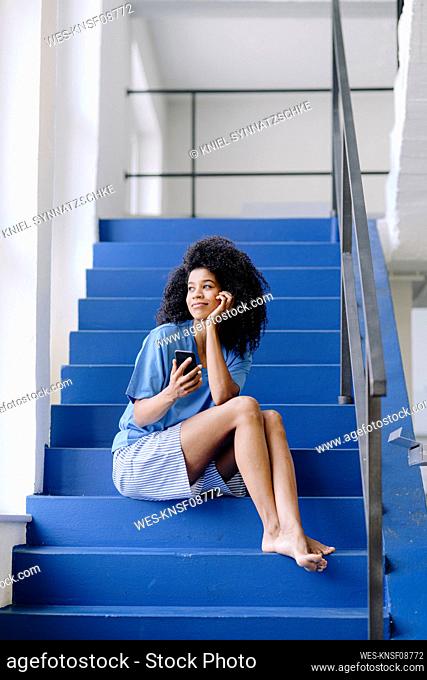 Mid adult woman with mobile phone contemplating on steps