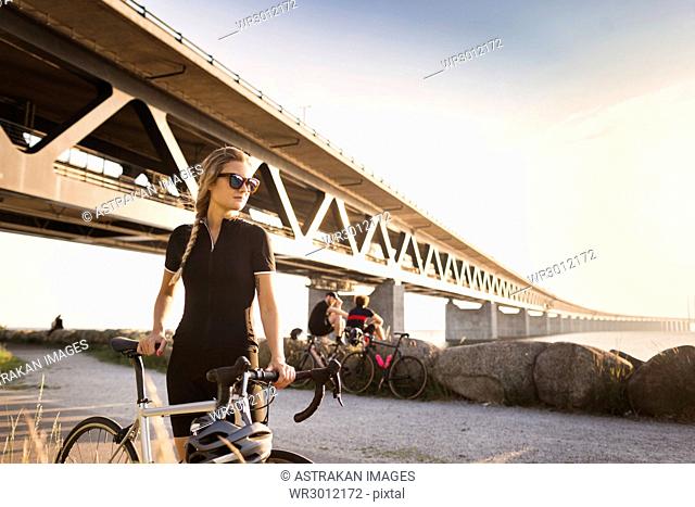 Woman with bicycle, two friends in background