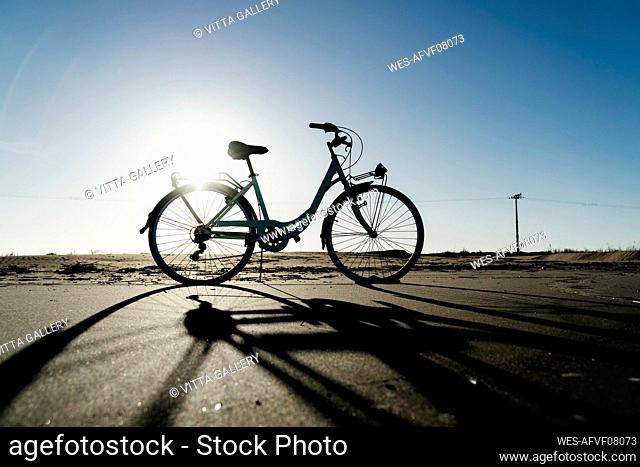 Silhouette bicycle parked at Fangar Beach against clear sky in sunlight, Ebro delta. Spain