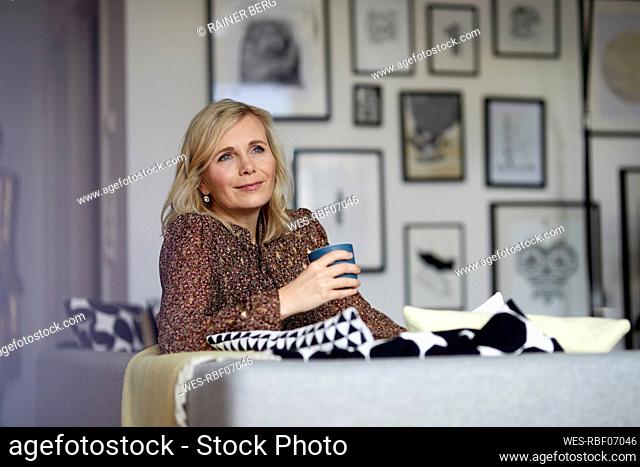 Blond woman relaxing at home sitting on couch