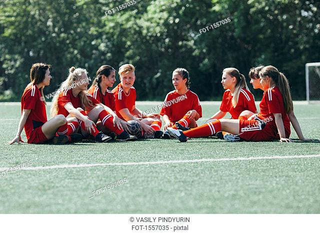 Female soccer team sitting on playing field