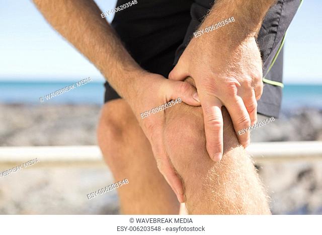 Fit man gripping his injured knee