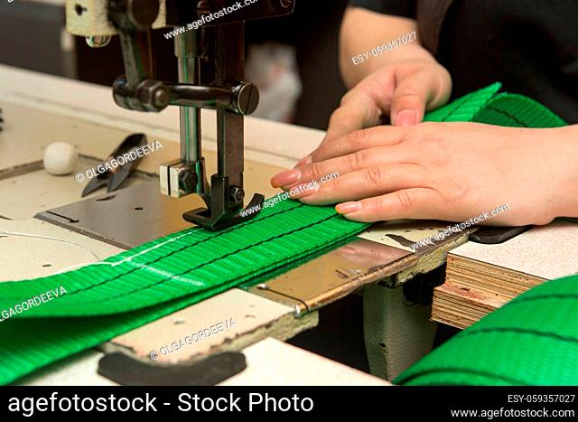 Industrial sewing machine sews a webbing sling. Manufacture of textile slings and tie straps