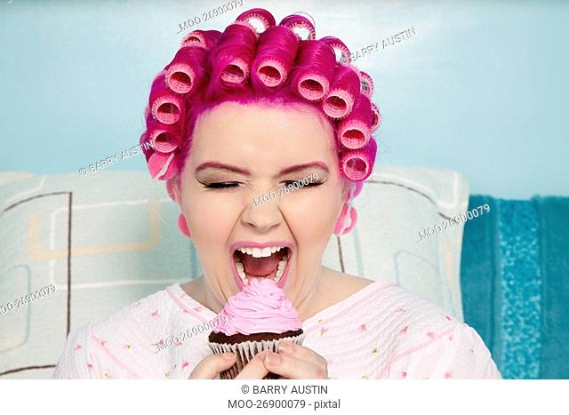 Young woman with open mouth holding cupcake