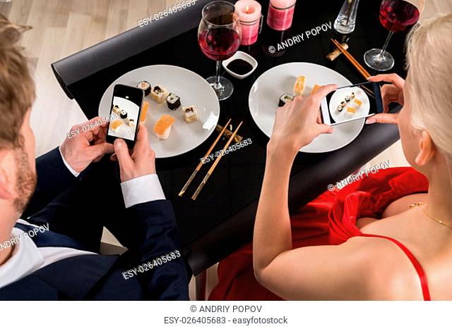 Young Couple Making Picture Of Food In A Restaurant