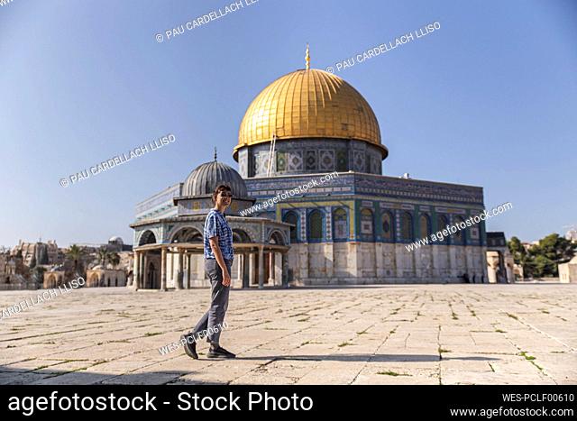 Young woman walking in front of Al-aqsa mosque on sunny day, Jerusalem, Israel