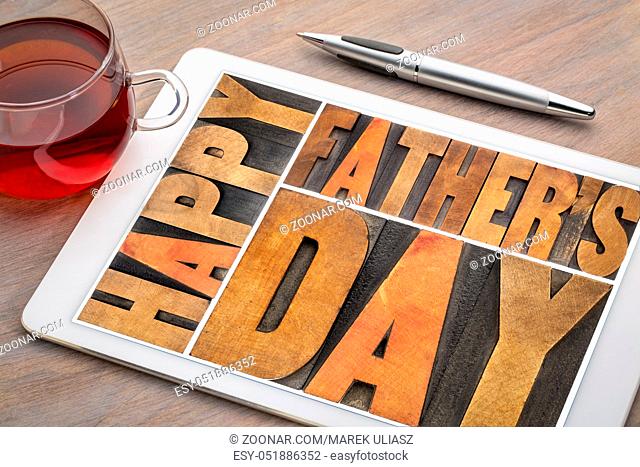 happy father's day - a word abstract in vintagewood letterpress printing blocks on a digital tablet with a cup of tea