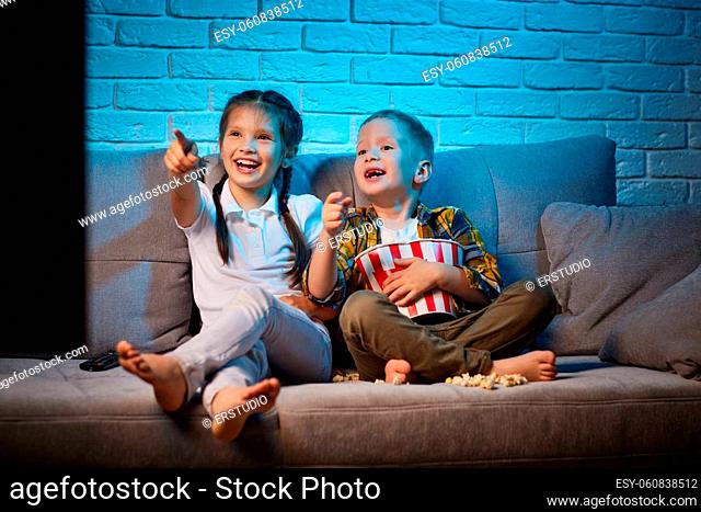 happy children sitting on sofa and watching cartoons