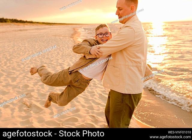 Happy father having fun with son on coastline at beach