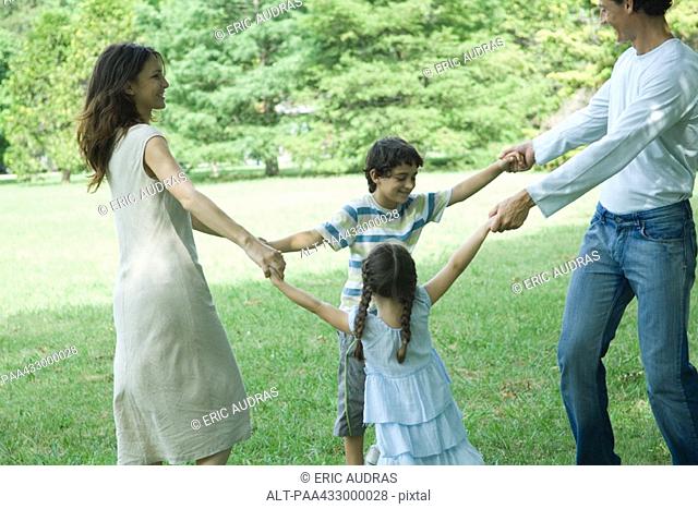 Family outdoors on lawn playing ring-around-the-rosy