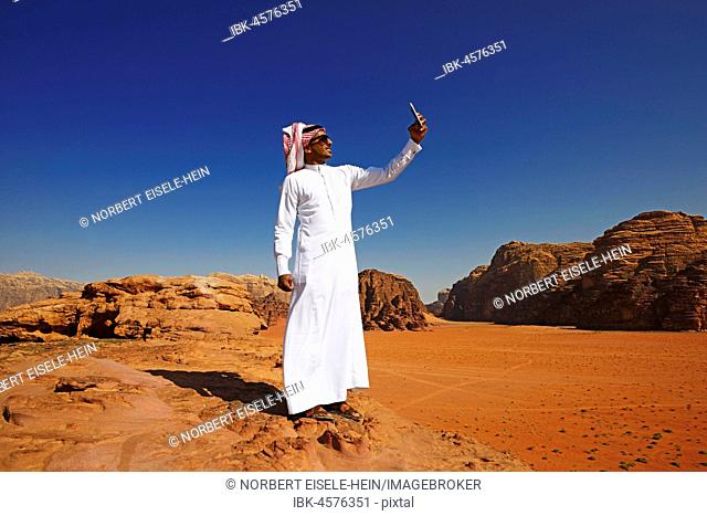 Bedouin uses his smartphone at Rock Arch, Al Borg Alsagheer, Wadi Rum, Jordan