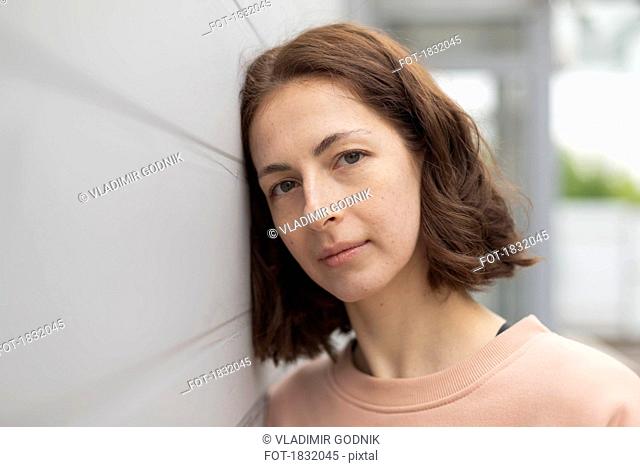 Portrait serene woman leaning against wall
