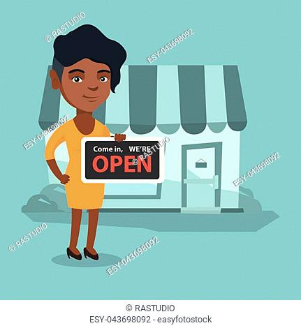 African-american shop owner holding a signboard with text open. Shop owner standing in front of small store. Young woman inviting to come in her shop