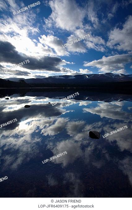 Scotland, Highland, Loch Morlich, Dramatic clouds and Cairngorm mountains reflected upon the still face of Loch Morlich