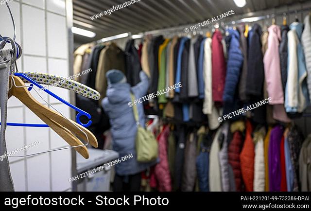 PRODUCTION - 28 November 2022, Berlin: A needy woman looks for a warm winter jacket at the Berlin Stadtmission clothing store