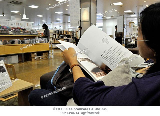 Naha (Japan): a woman reading a catalogue at Muji department store