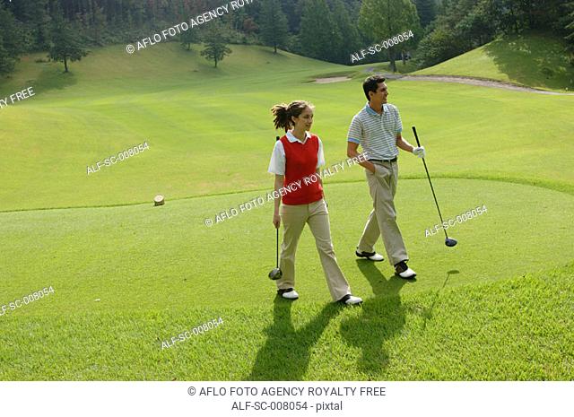 Couple walking down the fairway with their clubs