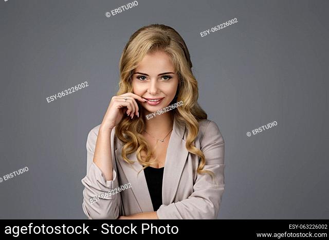 Portrait of happy curly business woman thinking about something on gray background