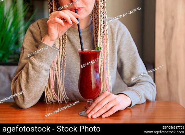 Young hipster woman kanekalons drinking berry cocktail smoothie with a straw