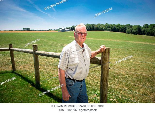 Grain producer standing by fence of farm with grain elevator in background Montgomery County Maryland USA