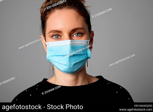 Portrait of young woman wearing face mask isolated on yellow background. Dust protection against virus. Coronavirus pandemic time