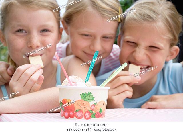 Three girls with tub of ice cream and wafers
