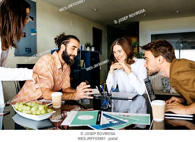 Friends working together on table at home sharing smartphone
