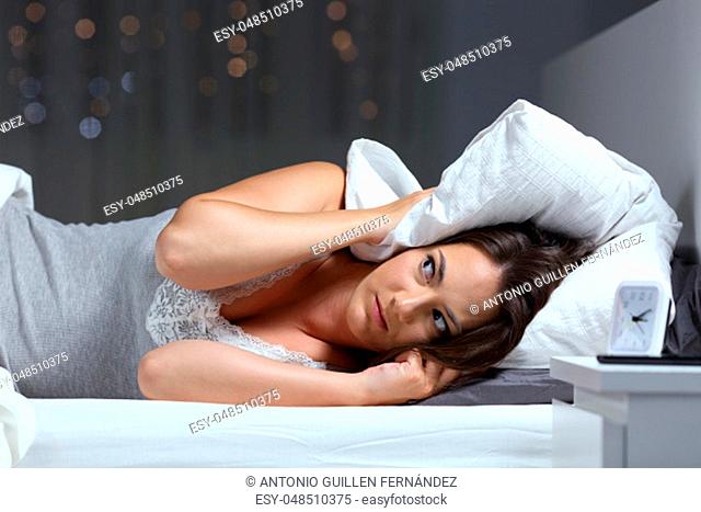 Desperate woman trying to sleep hearing neighbour noises in the night at home