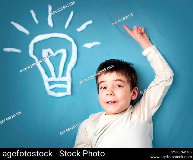 seven years old boy with a bulb on blue background. Child with an idea