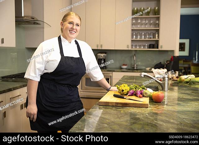 Portrait of Chef Megan Gill in kitchen looking up off camera, smiling