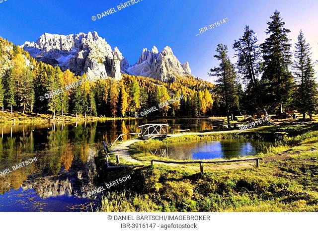 Autumn at Lake d'Antorno with a wooden bridge and the reflection of the Cadini Misurina Mountains, Dolomites, Belluno province, Veneto region, Alto Adige, Italy