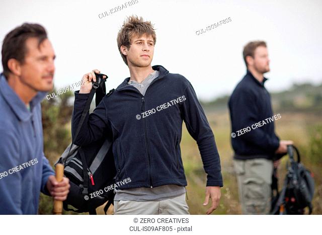 Three men hiking in rural landscape