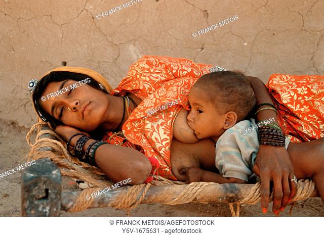 A hindu woman is sleeping while her baby is suckling. From a village in Thar desert, Rajasthan, India