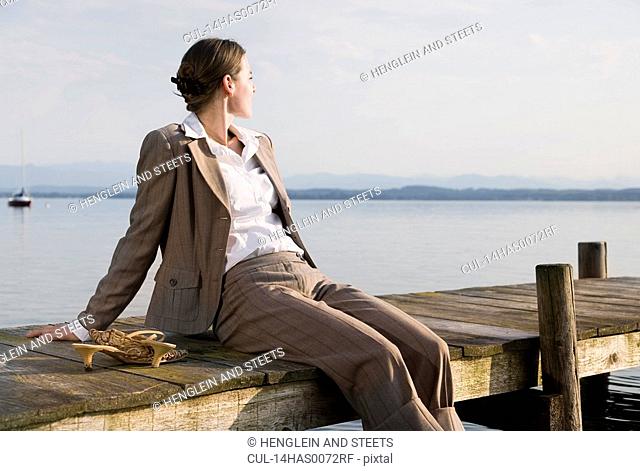 woman sitting on pier at lake