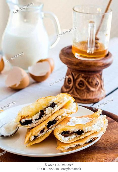 thin pancakes stuffed with cheese, prunes and sour cream, milk