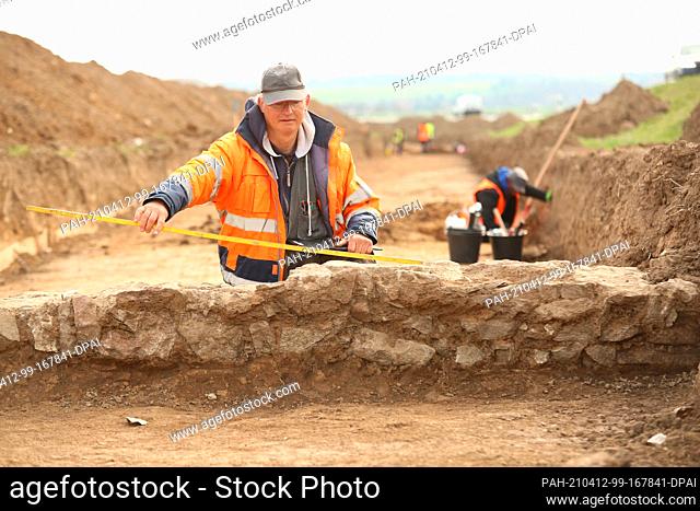09 April 2021, Saxony-Anhalt, Derenburg: Excavation leader Christian Rauh misses uncovered parts of a drainage system. Archaeological investigations are...