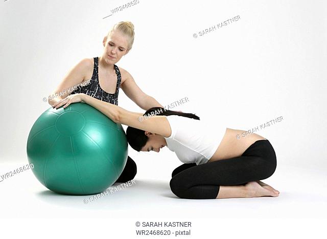 Pregnant woman doing fitness exercise with a personal trainer