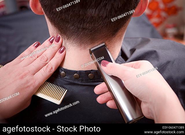 Man#39;s hairstyling and haircutting with hair clipper in barber shop or hairdressing salon. Closeup picture