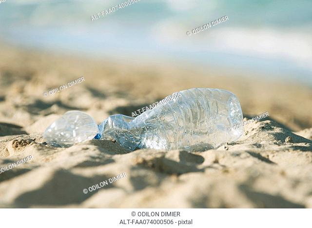 Empty plastic bottle on beach, selective focus