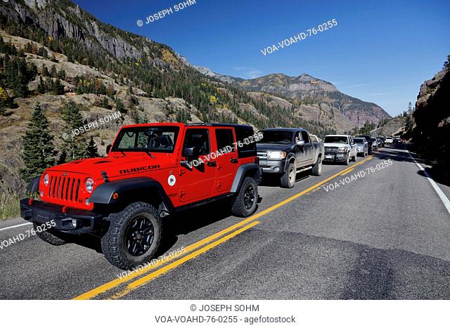 Red jeep and cars are delayed on Million Dollar Highway Route 550 out of Ouray Colorado during road repairs