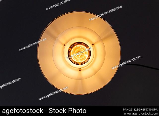 PRODUCTION - 25 November 2022, North Rhine-Westphalia, Cologne: ILLUSTRATION - A lamp lights up over a dining room table