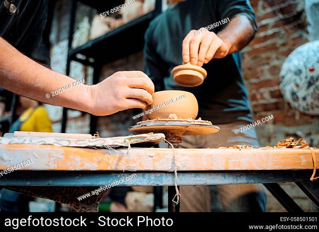 Friends working on clay on a potter's wheel. Making a handmade clay pot. Pottery lesson, hobby