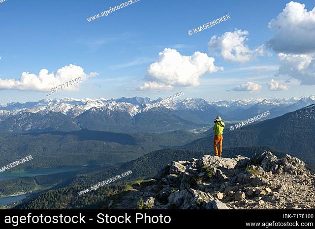 Hiker taking photos at the summit of Heimgarten, view into the distance, Karwendel Mountains in the background, ridge walk Herzogstand Heimgarten, Upper Bavaria