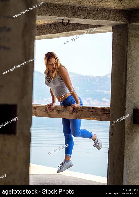Teengirl exercising jumping balancing on wooden beam post looking down away