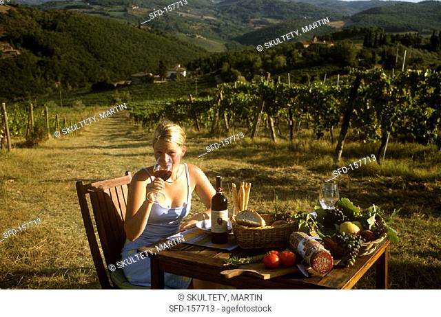 Woman drinking a glass of Chianti in a Tuscan vineyard