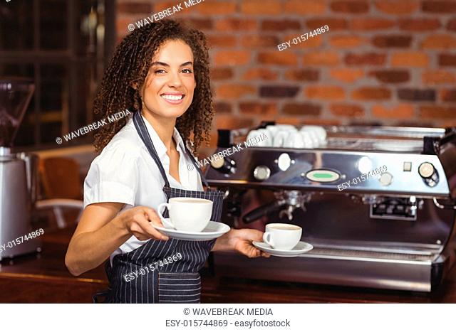 Smiling barista holding two cups of coffee