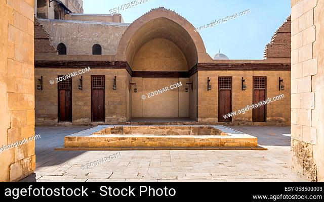Courtyard of public historic mosque of Sultan Al Nassir Qalawun with side arched iwan and closed wooden doors, Cairo, Egypt