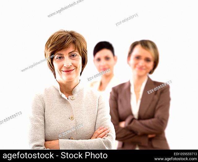Happy businessteam of three businesswomen standing in front of windows inside officebuilding, smiling, senior businesswoman leading. Isolated on white