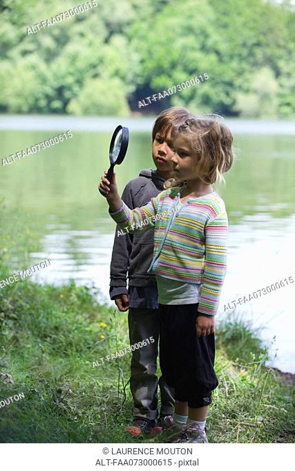 Children playing with magnifying glass outdoors