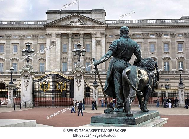 Bronze statue of a man and a lion and tourists in front of Buckingham Palace, London, England, Great Britain, Europe